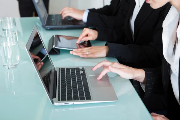 Empresarios que trabajan en computadoras portátiles y tabletas — Foto de Stock