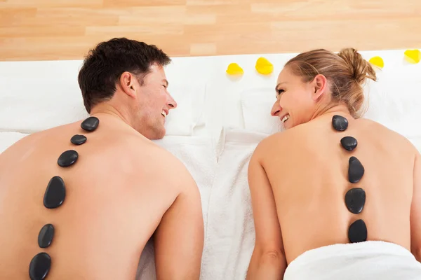 Casal desfrutando de uma massagem de pedra quente — Fotografia de Stock