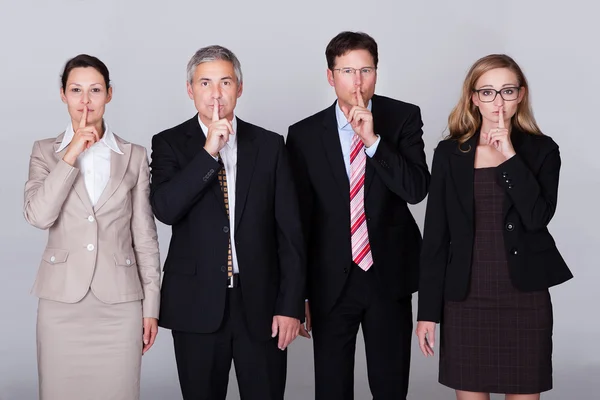 Cuatro empresarios haciendo gestos de silencio — Foto de Stock