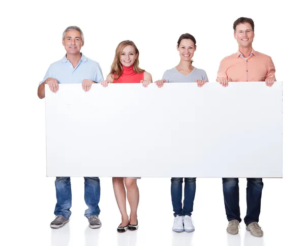 Two happy couples holding up a blank banner — Stock Photo, Image