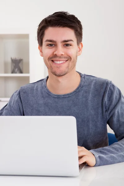 Jovem sorridente usando um laptop — Fotografia de Stock