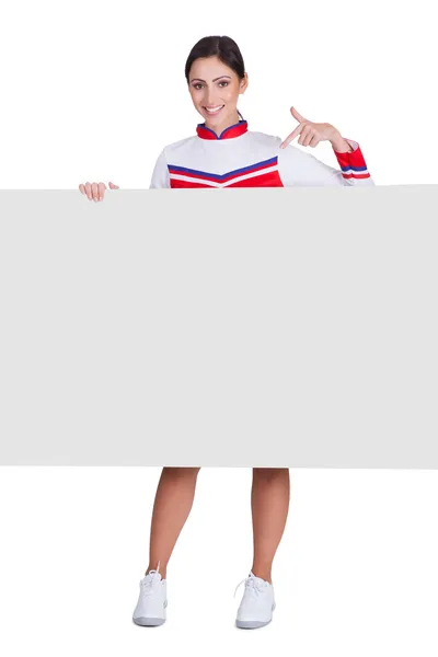 Cheerleaderka, wskazując na puste afisz — Zdjęcie stockowe
