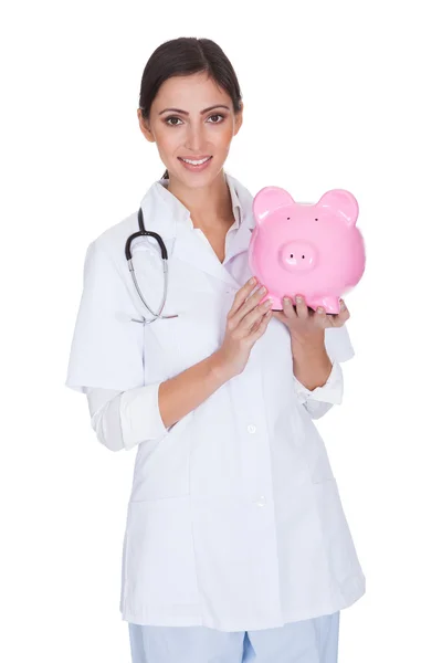 Jovem médico segurando porquinho banco — Fotografia de Stock