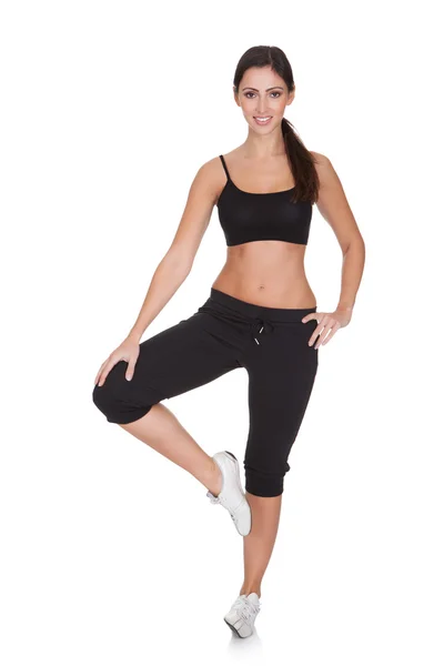 Jovem mulher se exercitando enquanto está de pé em uma perna — Fotografia de Stock