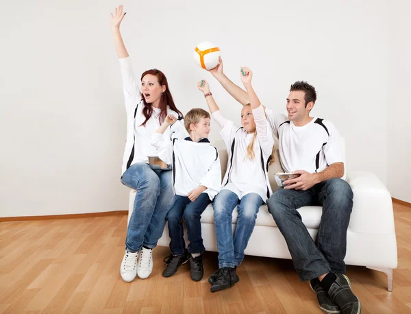 Familia joven viendo el partido de fútbol en casa — Foto de Stock