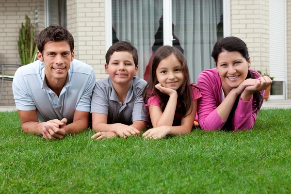 Porträtt av glada unga familj liggande på gräs — Stockfoto