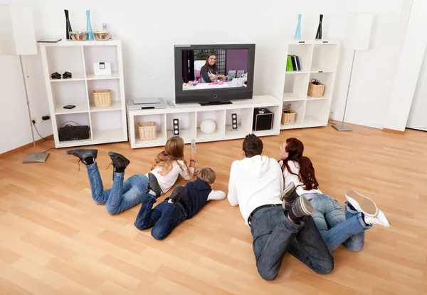 Молодая семья смотрит телевизор дома — стоковое фото