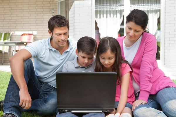 Familia joven en el patio trasero usando el ordenador portátil —  Fotos de Stock