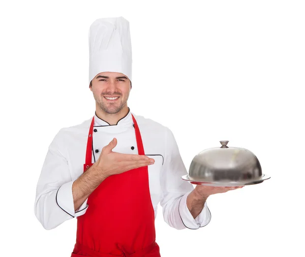 Portrait of cheerful chef presenting silver tray — Stock Photo, Image