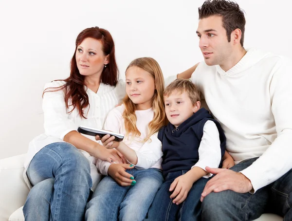 Cheeful unga familjen tittar på tv hemma — Stockfoto