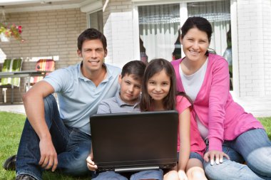 mutlu bir aile laptop ile birlikte oturan