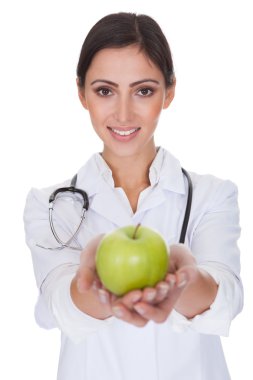Yeşil elma tutan genç bir kadın doktor