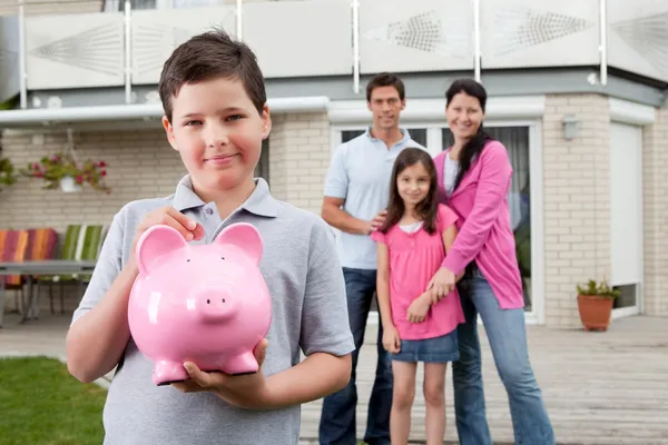 Маленький мальчик экономит деньги с семьей на заднем дворе — стоковое фото