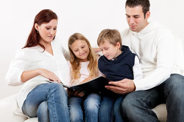 Glückliche junge Familie schaut sich Fotoalbum an — Stockfoto