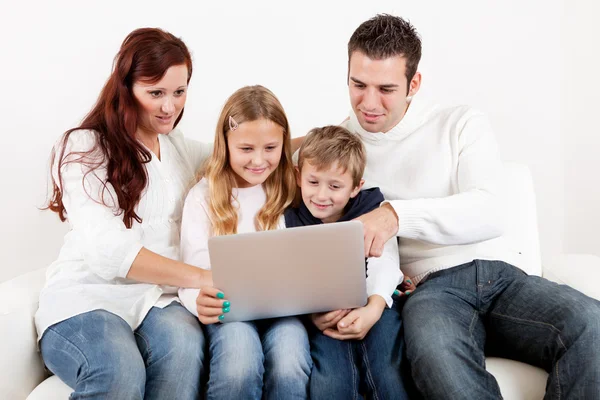 Familia feliz usando el ordenador portátil en casa — Foto de Stock