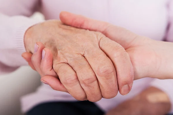 Junge Frau hält Seniorin die Hand — Stockfoto