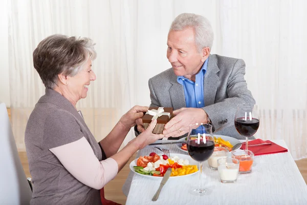 Hombre mayor dando regalo a la mujer mayor — Foto de Stock