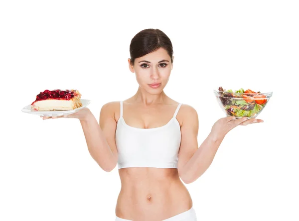 Jovem mulher segurando bolo e salada — Fotografia de Stock