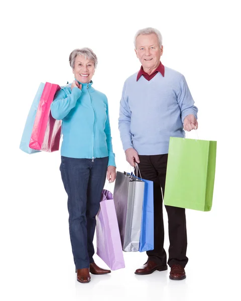 Casal sênior segurando sacos de compras — Fotografia de Stock