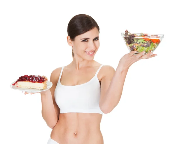 Junge Frau mit Kuchen und Salat — Stockfoto