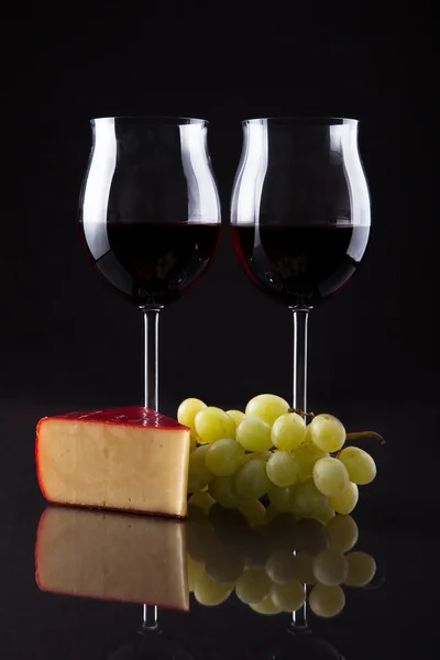 Botella de vino, vidrio, queso y uva aislados sobre fondo negro —  Fotos de Stock