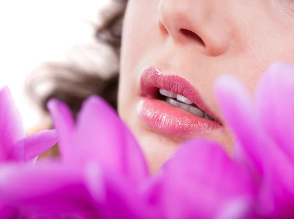 Jonge vrouw voor paarse bloemen — Stockfoto