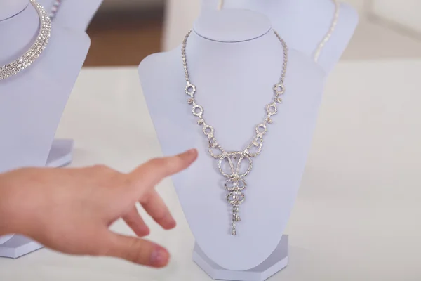 Woman\'s Hand Choosing Diamond Necklace In Shop