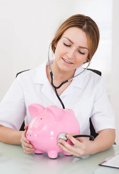 Female Doctor Examining Piggybank — Stock Photo, Image