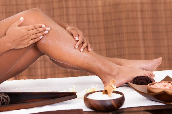 Mujer joven aplicando aceite en sus piernas — Foto de Stock