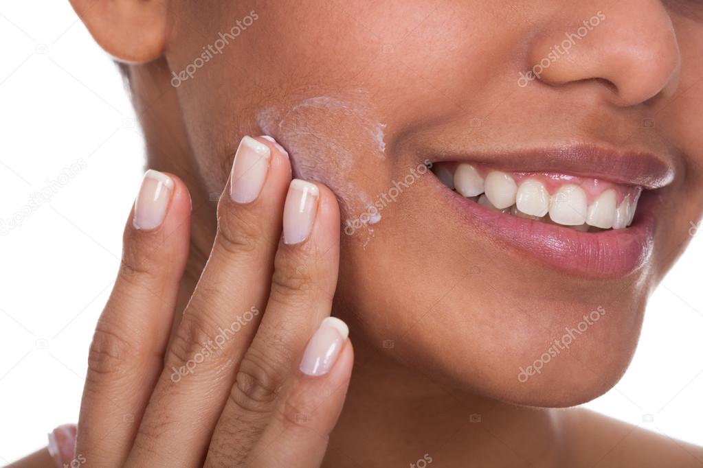 Young Woman Applying Cream On Her Face