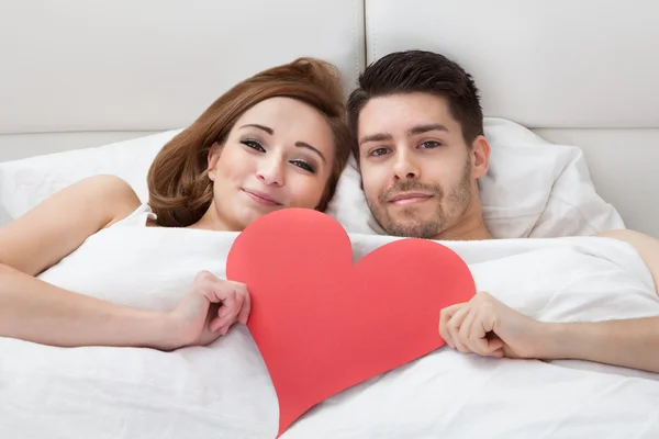 Portrait of young loving couple lying on bed — Stock Photo, Image