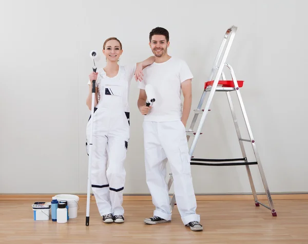 Jovem casal segurando rolo de pintura — Fotografia de Stock