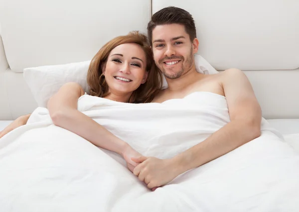 Retrato de pareja joven y feliz acostada en la cama —  Fotos de Stock