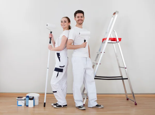 Jovem casal segurando rolo de pintura — Fotografia de Stock