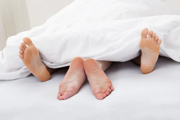 Gros plan des pieds du couple dormant sur le lit — Photo