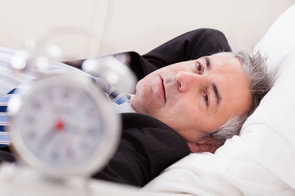 Reloj despertador delante del hombre durmiendo — Foto de Stock