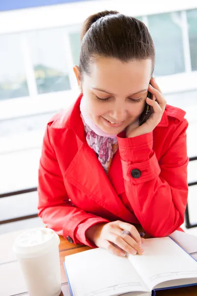 Šťastná žena při pohledu na deník a mluví do mobilního telefonu — Stock fotografie