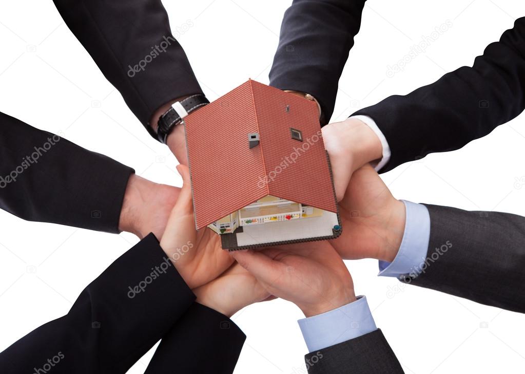 Group Of Businesspeople Holding Model House