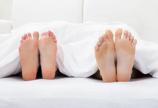 Gros plan des pieds du couple dormant sur le lit — Photo