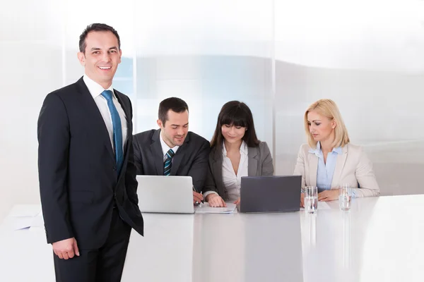 Mann steht vor Kollegen, die im Büro arbeiten — Stockfoto