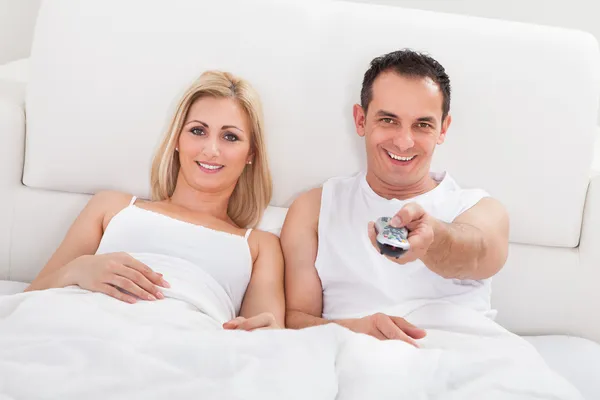 Casal relaxante na cama assistindo televisão — Fotografia de Stock