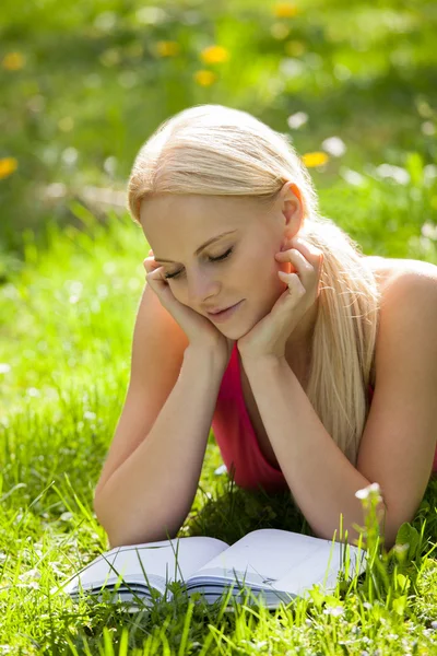 Ung kvinna i park läser bok — Stockfoto