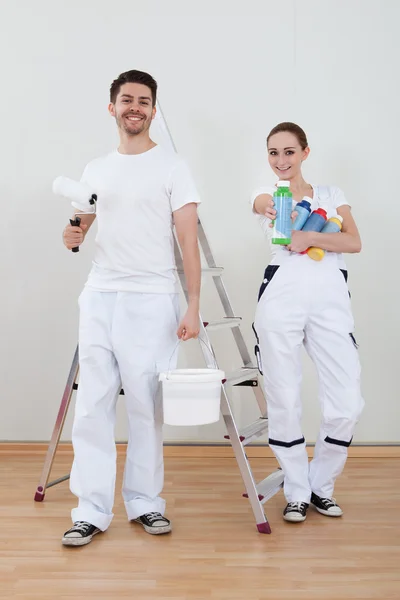 Jovem casal segurando rolo de pintura — Fotografia de Stock