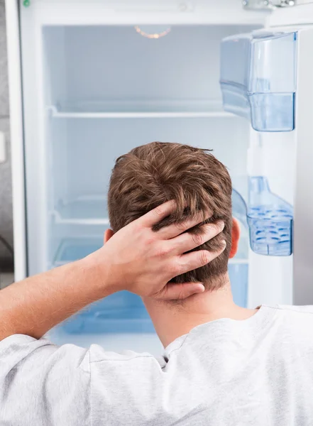 Hombre reflexivo buscando en el refrigerador vacío — Foto de Stock