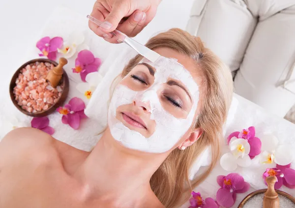 Kosmetikerin trägt Gesichtsmaske auf Gesicht der Frau auf — Stockfoto