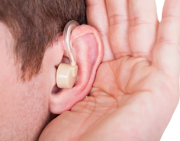 Homem vestindo aparelho auditivo e audição para um som silencioso — Fotografia de Stock