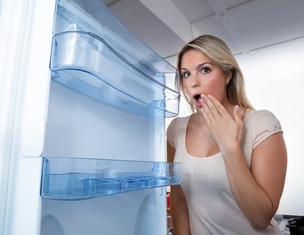 Жінка дивиться в порожній холодильник — стокове фото