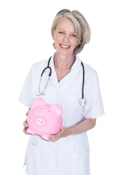 Mature Female Doctor Holding Piggybank — Stock Photo, Image