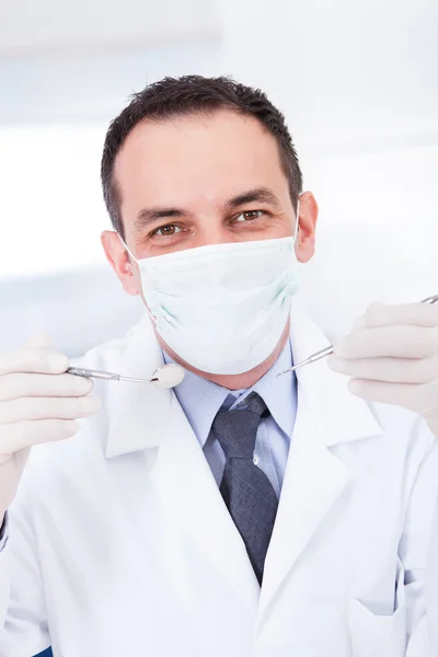 Retrato de dentista masculino segurando espelho angulado e carver — Fotografia de Stock