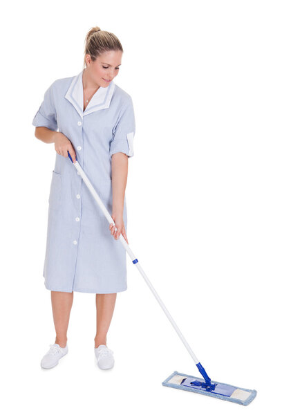 Молодая горничная моет пол шваброй
